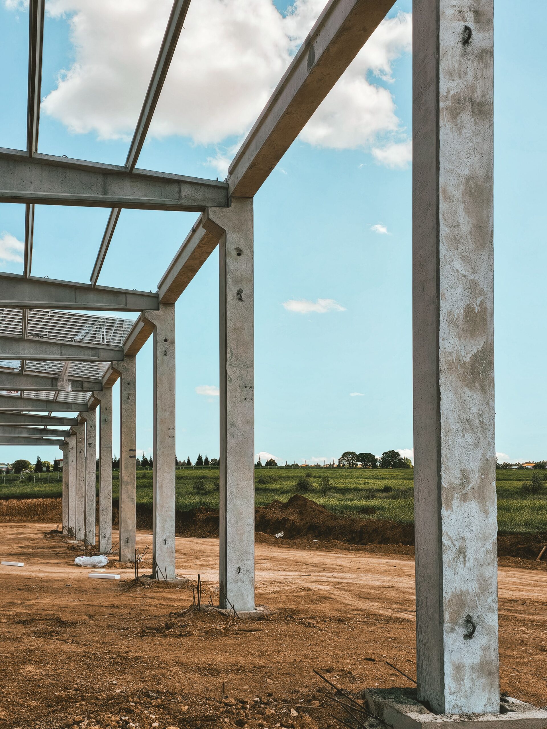 Concrete pillars in a rural setting form part of a new building structure under construction.
